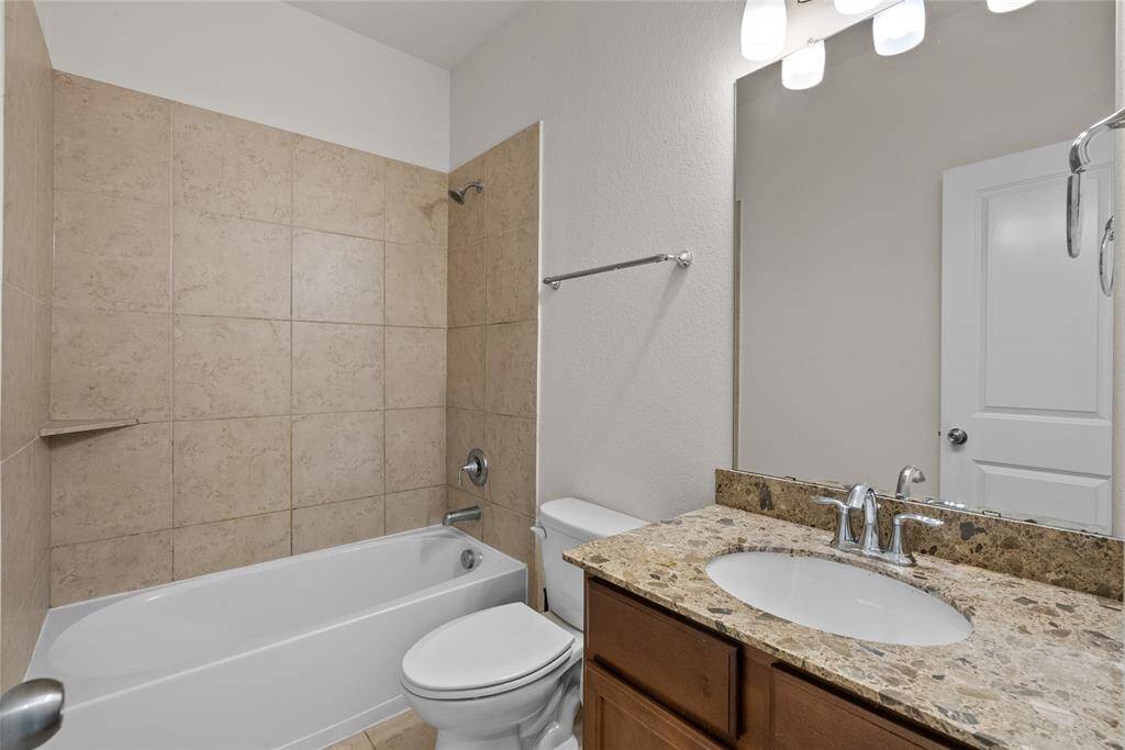 Modern bathroom featuring a bathtub,  sink vanity with granite countertop, and a large mirror with overhead lighting. It has a clean, neutral color scheme.