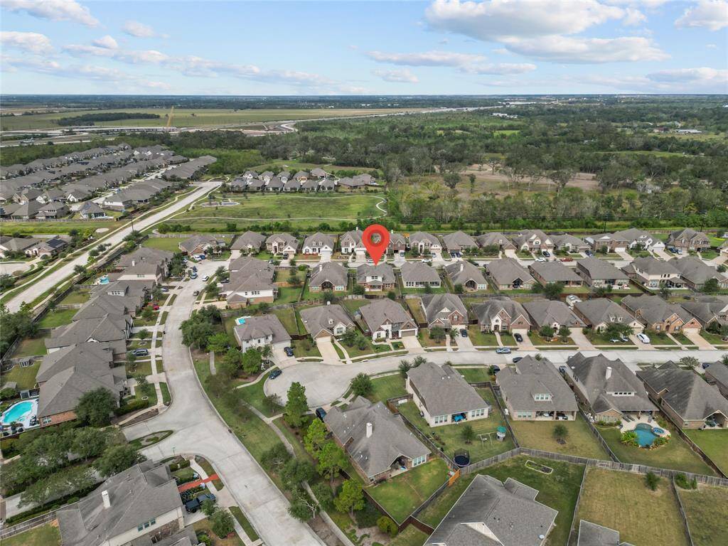 This is an aerial view featuring a mix of single-family homes with curving streets, and there's open green space nearby. Walking spaces and lots of lakes Steps from school