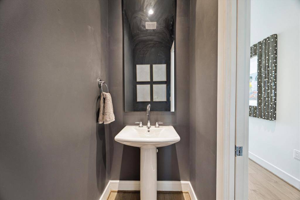 The half bath for guests features a pedestal sink and is located off the entry.