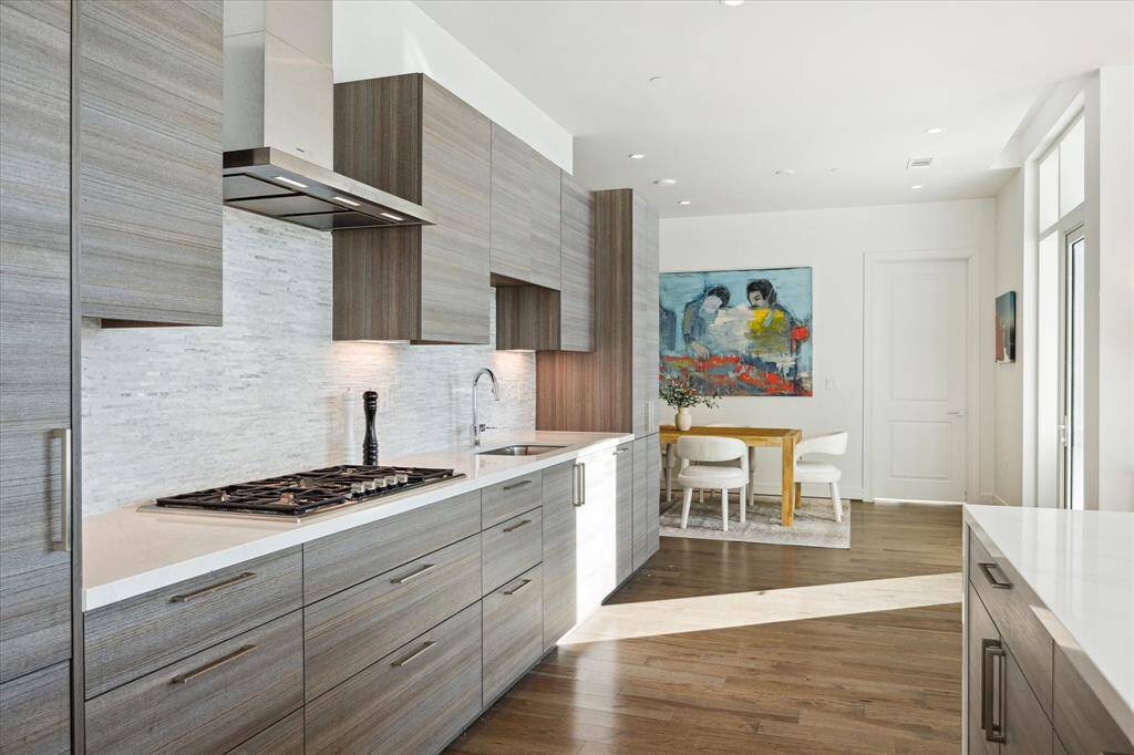 This modern kitchen features Eggersman kitchen cabinetry, Gaggenau stainless steel appliances, a waterfall island, and gas cooktop.