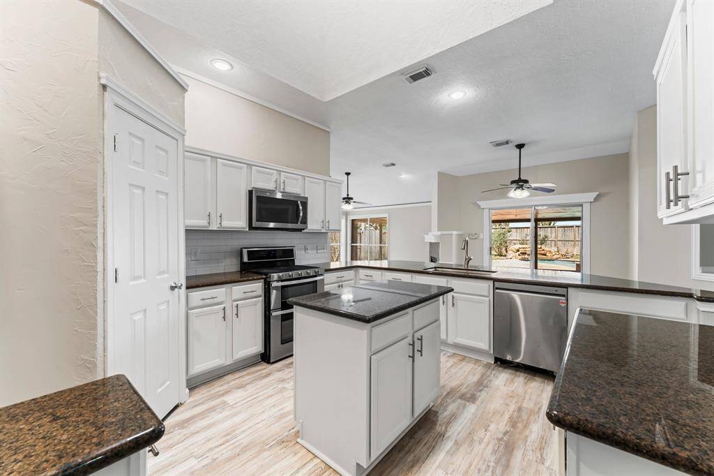 Granite Island Kitchen boasting Stainless Appliances, Corner Pantry, Gas Cooking & Double Oven, Large Farm Sink, Tons of Countertops and Corner Pantry with Huge Counter Height Breakfast Bar Open to Breakfast Area and Great Views of Back Yard and Pool!