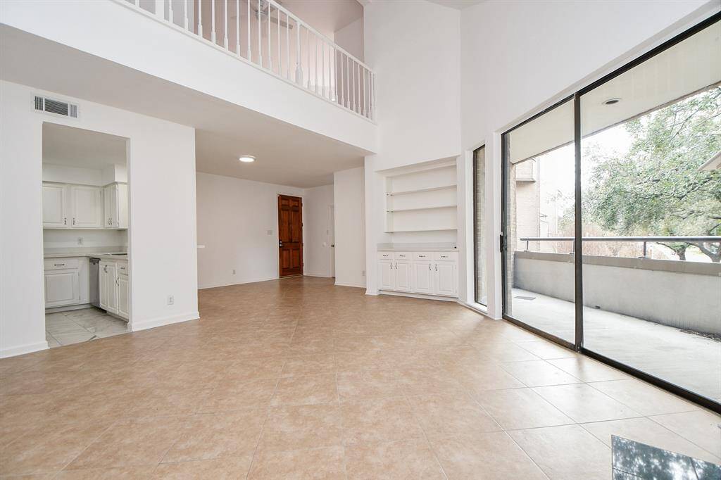 This amazing view of the incredible, bright living area, also includes a peek into the kitchen and a look upwards, to the 2nd floor railing.