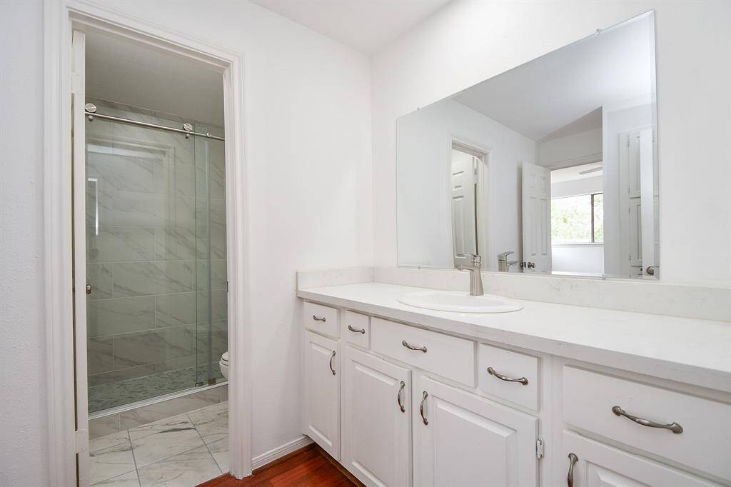 Creamy white walls and cabinetry fill the primary ensuite bath, with private shower/commode, left.