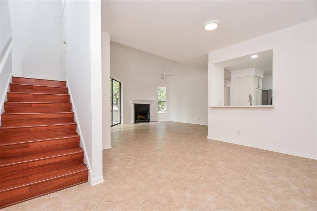 Wide open, airy space fills the 1,764 square-foot unit condo comprised of high ceilings, neutral toned walls and tile flooring, with a warm view of the wood staircase, on this 1st floor living area to the 2nd level, left. Inside this special home are 2 bedrooms, 2 baths.