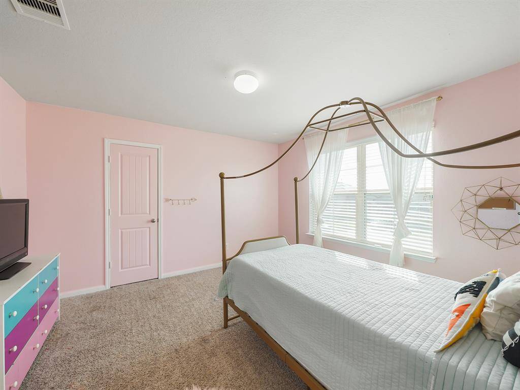 This spacious secondary bedroom is filled with natural light from large windows, creating a warm and inviting atmosphere.