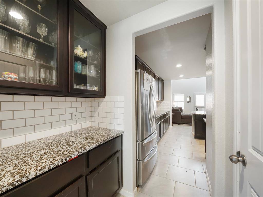 The butler-style pantry seamlessly flows into the kitchen, offering additional storage and prep space while maintaining a sleek and functional design.