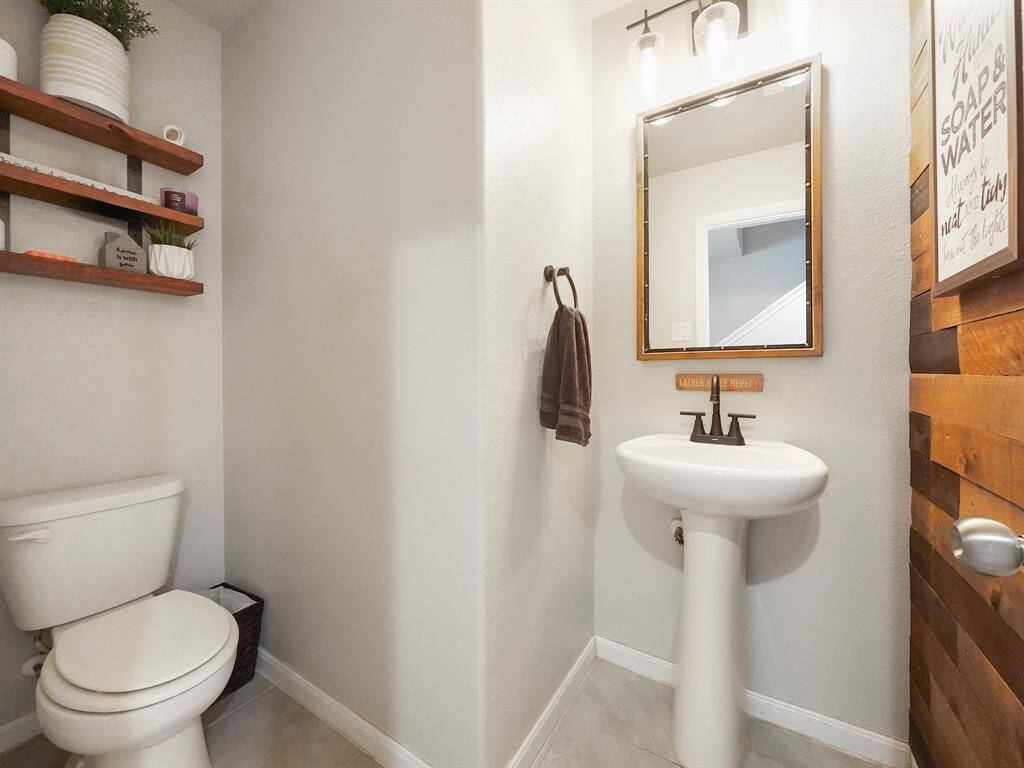 This downstairs half bath offers a modern touch with sleek fixtures, warm wood accents, and open shelving for extra storage. A perfect blend of functionality and design!