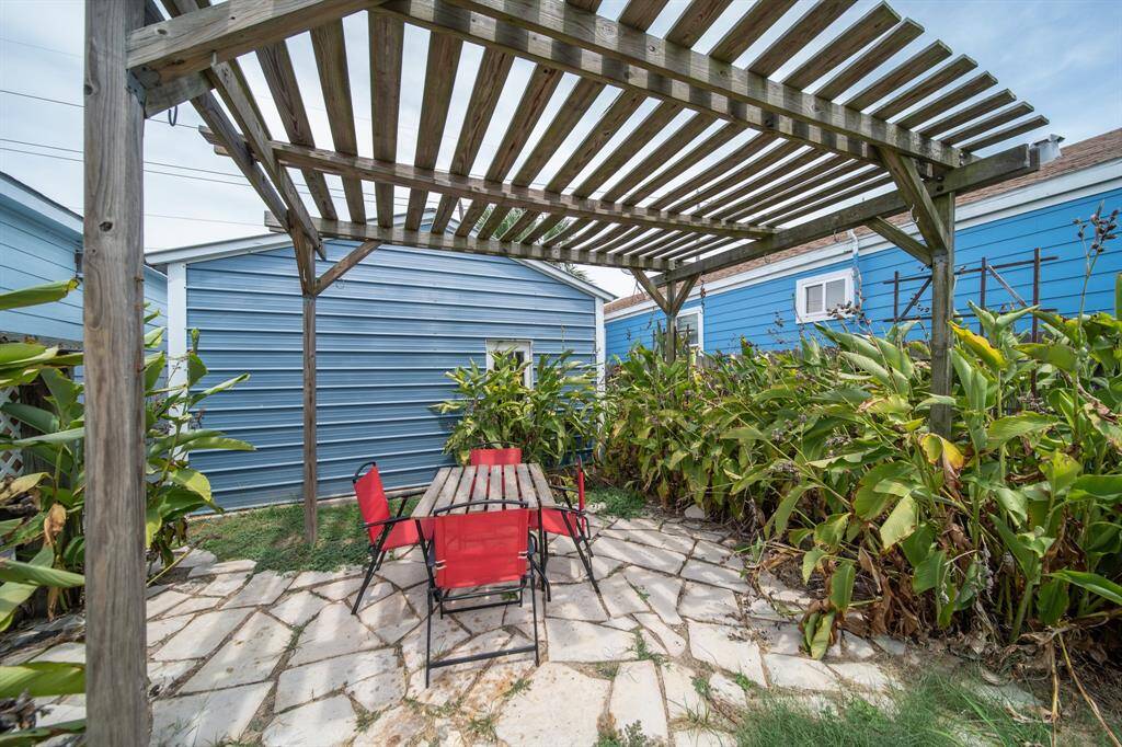 Relax at this outdoor dining area resting under a pergola.