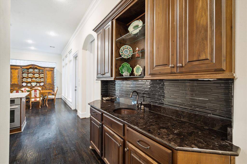 Notable is the BUTLER'S PANTRY with its stained wood cabinetry/glass display shelving, granite counter, decorative tile backsplash, hammered copper sink, under cabinet lighting.