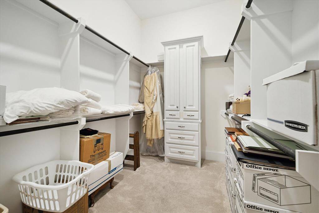 One of two PRIMARY CLOSETS - this one includes carpeted flooring, built in hanging compartments, builtin cabinet and drawers.