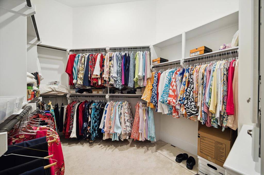 The second PRIMARY CLOSET includes carpeted flooring, hanging compartments and shelving above.