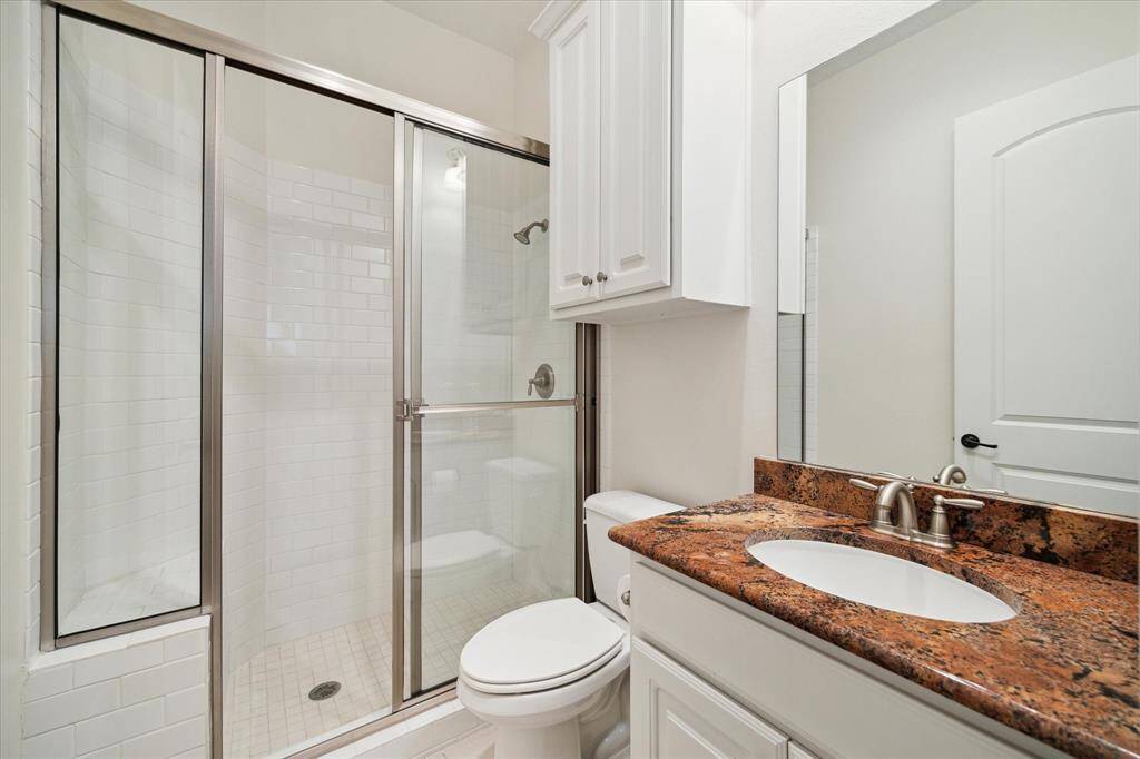 EN SUITE BATH is appointed with granite counter/backsplash, oval shaped sink with painted cabinet below, mirror with light fixture above, buil-in linen storage, walk in shower with sliding glass door/built in bench, white subway tile surround.