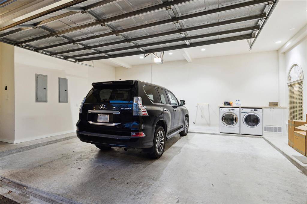 Spacious and high ceilinged two car GARAGE with storage closet, space for a full sized washer/dryer, cabinet closet, two windows with blinds/fan shaped transoms above.