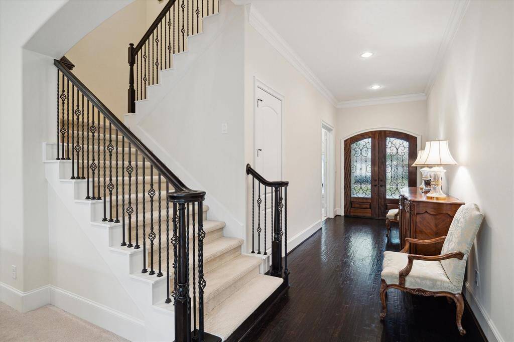 View from the Living Room showing the FRONT STAIRWAY with its detailed wrought iron spindles, wood railing and carpeted stairs. A secondary stairway is found in the rear portion of the home near the Kitchen and Utility Room.