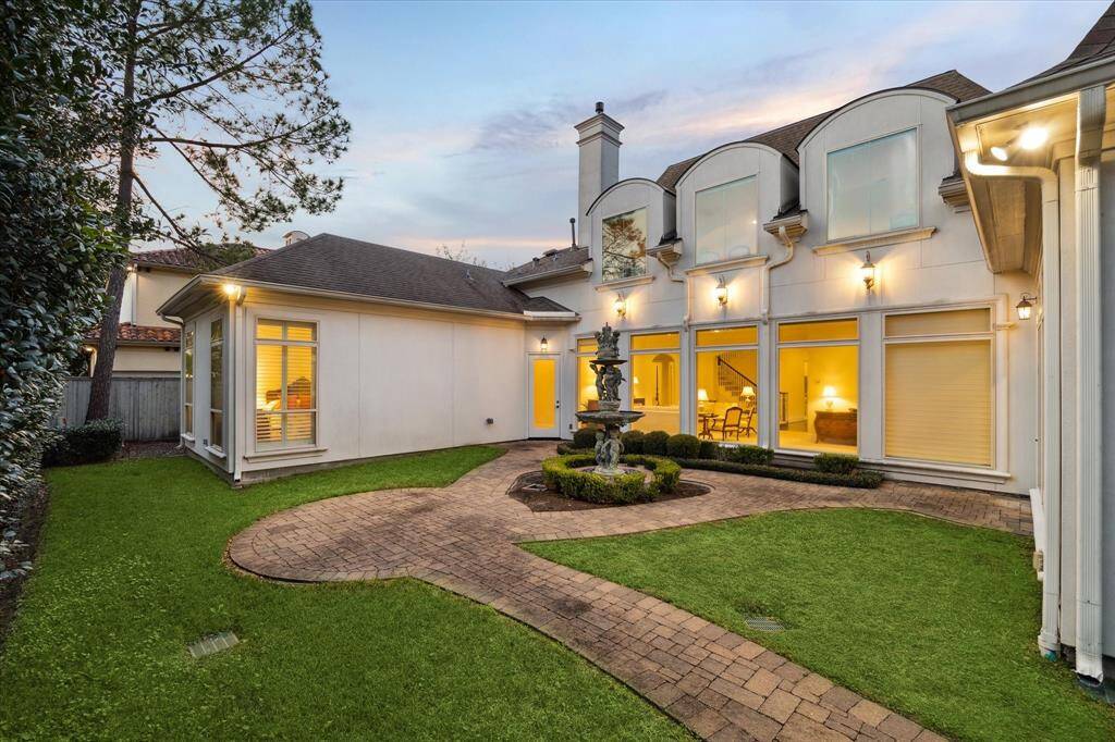 View from the southeast side of the BACKYARD showing the Primary Bedroom wing and the Living/Dining interior rooms with their series of four expansive windows overlooking the outdoor space.