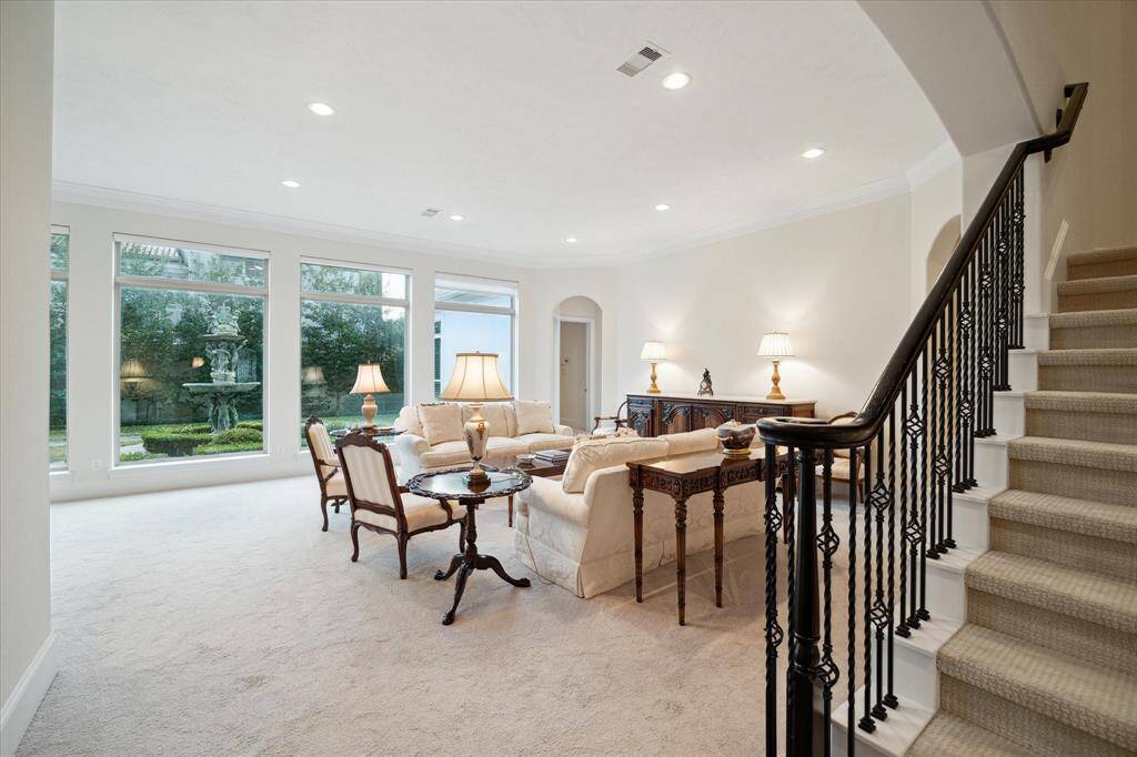 A generously sized LIVING ROOM (21 X 20) is brightly lit by a series of expansive windows allowing natural light to filter into the entertaining space (electronic shades allow for easy covering).  Also included are carpeted flooring, recessed lighting, painted walls, crown/base molding, arched entry to Primary Bedroom and the downstairs Guest Bedroom.