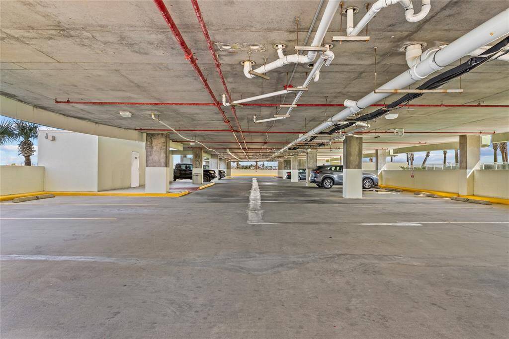 This photo shows a well-lit, covered parking garage with multiple parking spaces. This is one of two levels.  Condo conveys with 2 parking spaces.