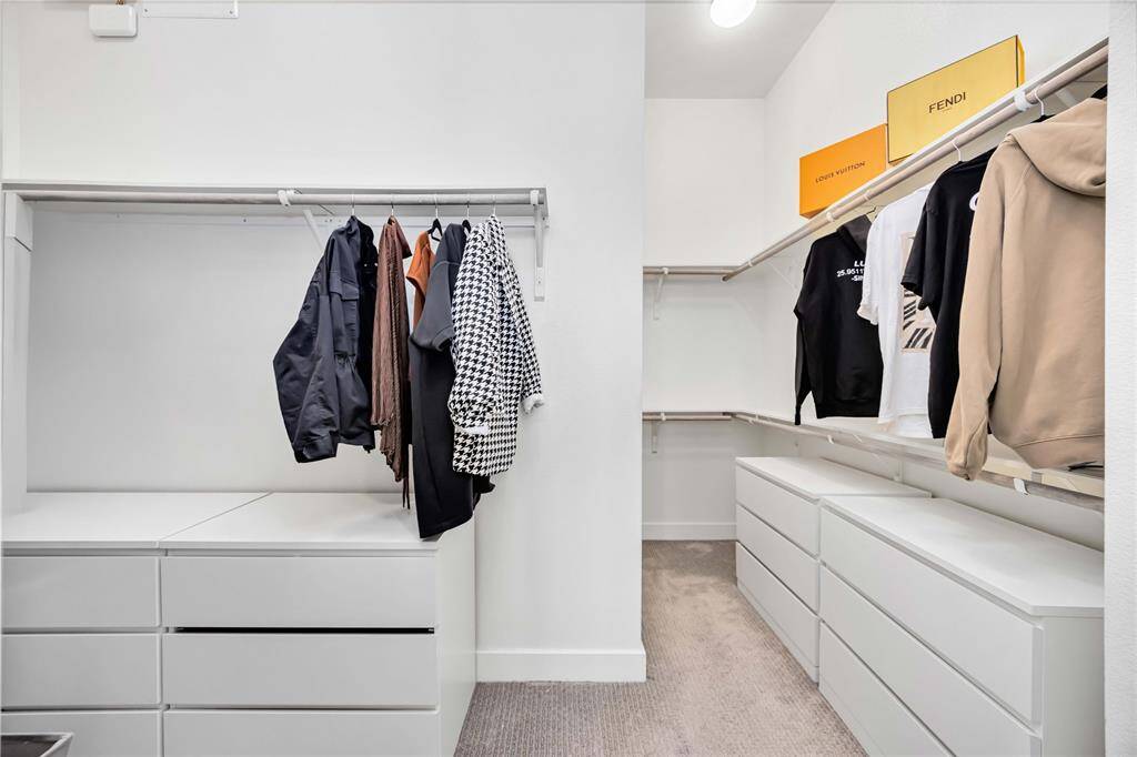 This is a spacious walk-in closet featuring ample hanging space, multiple white drawers, and shelving for storage. Perfect for organizing clothing and accessories.