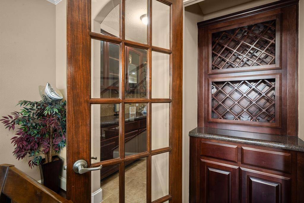 This photo features a cozy wine storage area with rich wooden cabinetry and a glass-paneled door, creating an elegant and inviting space.