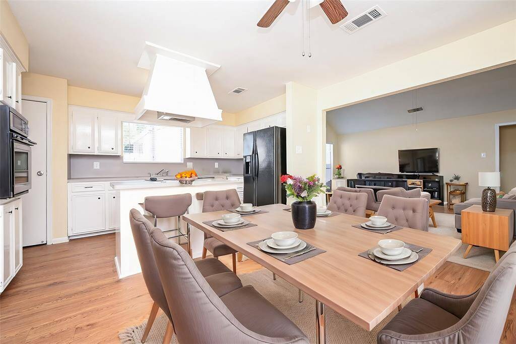 Check out this awesome kitchen with white cabinetry, laminate countertops, and plenty of storage. The room is finished with wood-like flooring and has a view into the adjoining living area, creating a great flow to keep everyone connected!