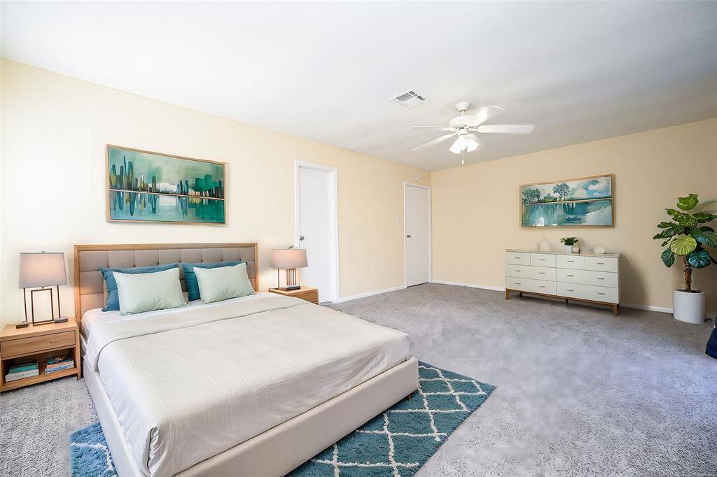 You're looking at a spacious room with neutral walls and a textured carpet. It features a ceiling fan and ample natural light, with a clean and blank canvas suitable for personalization.