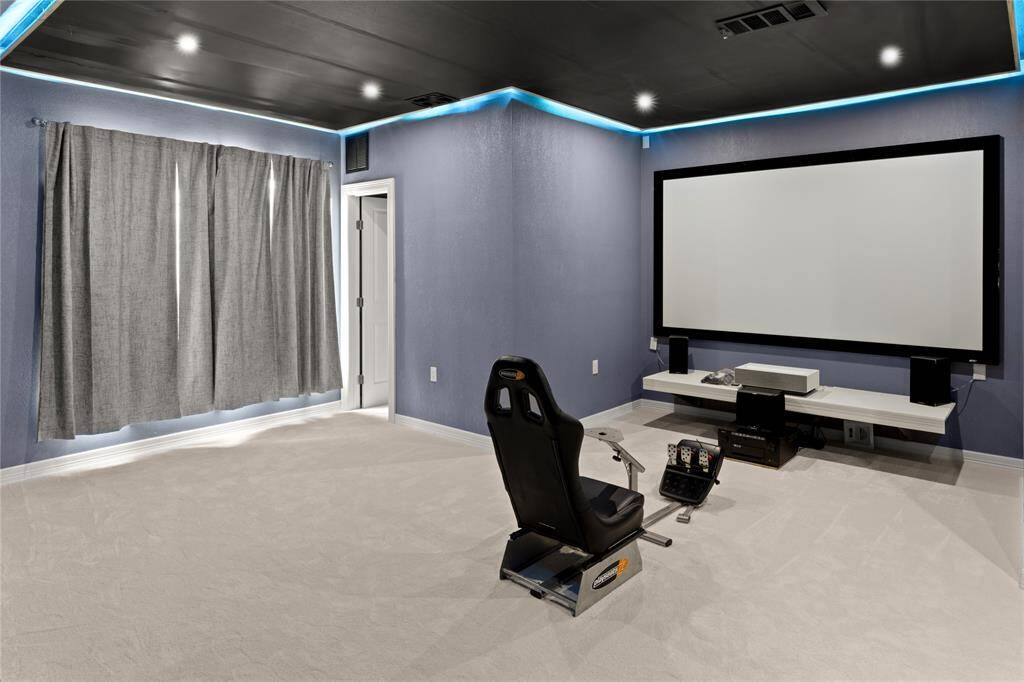 This versatile media room features a screen, custom lighting, two storage closets, a window, and a private door, making it a potential 6th bedroom.