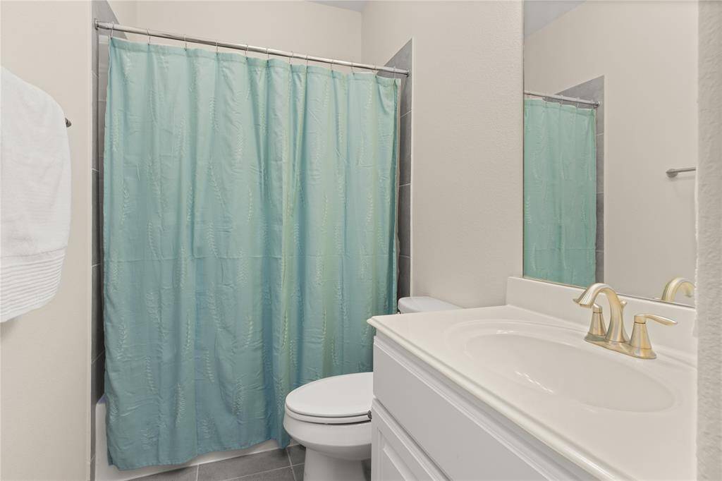 Convenient full bath near the secondary bedroom, featuring a spacious vanity and a linen closet.