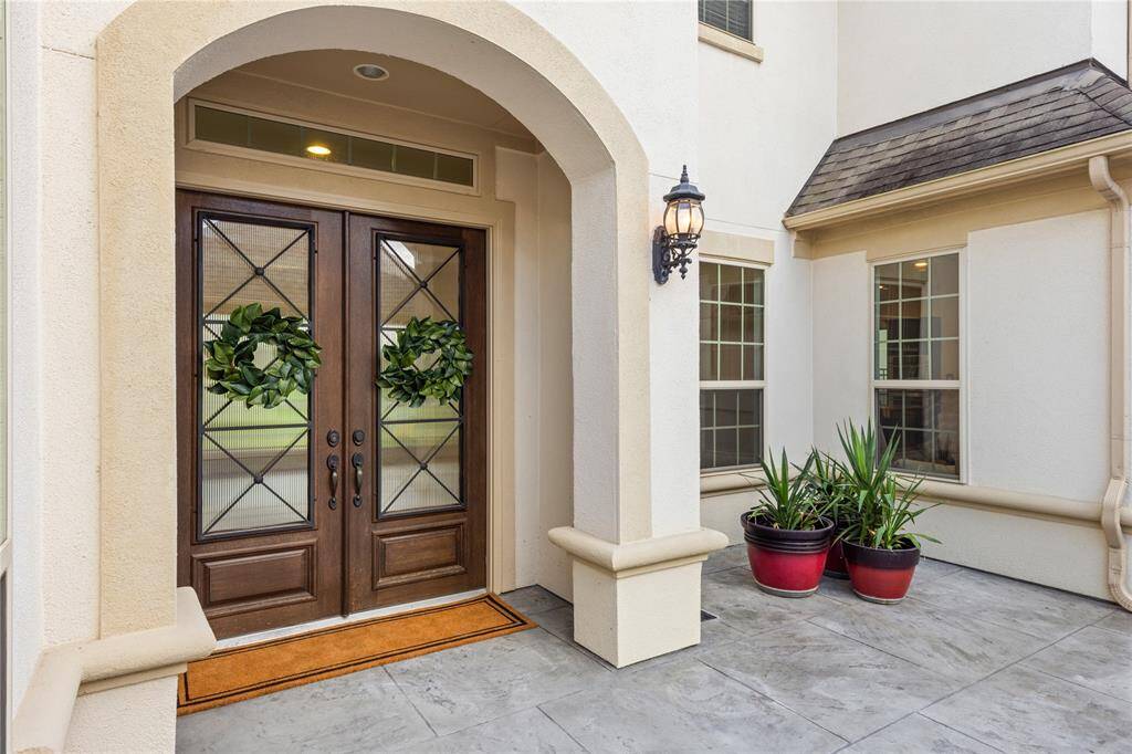 Stunning wooden double doors with beveled glass and elegant wrought iron details.
