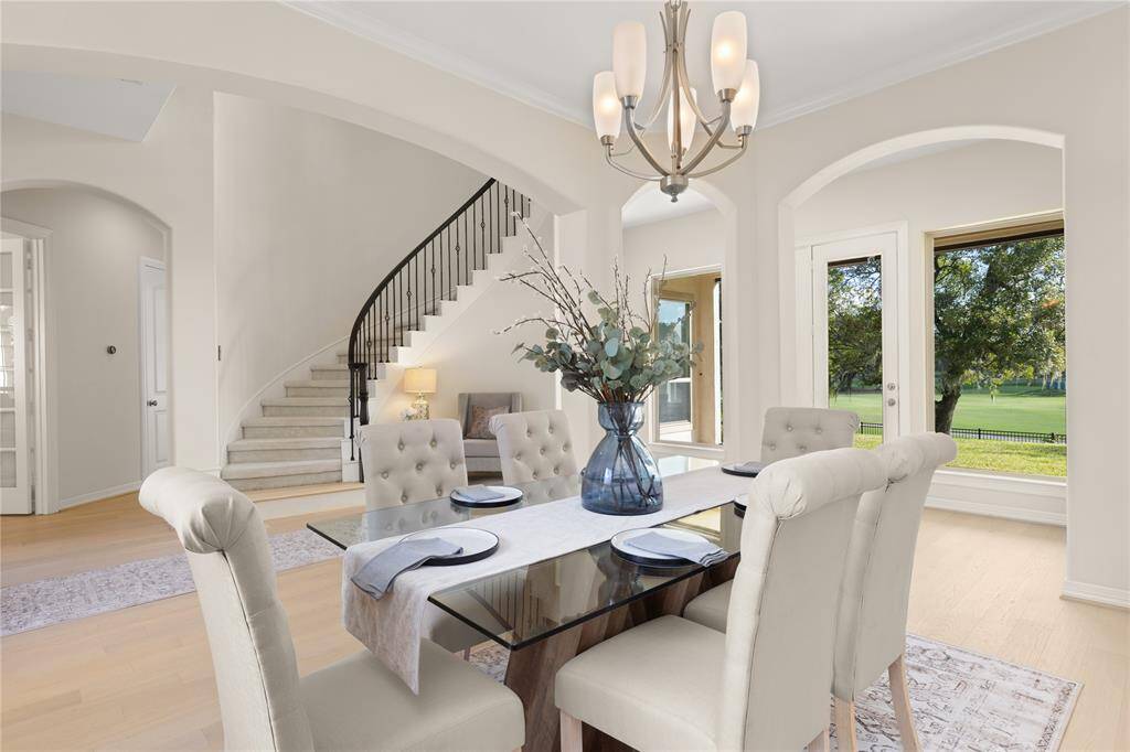 Another view of the dining room with a view of the curved staircase and scenic golf course.
