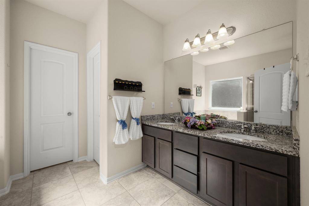 The private primary en-suite has two sinks and lots of cabinets for storage, beautiful tile floors and granite counter tops.