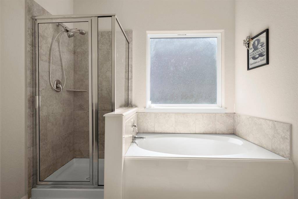 This primary bathroom has a large tiled shower and separate soaking tub that promotes a spa experience.