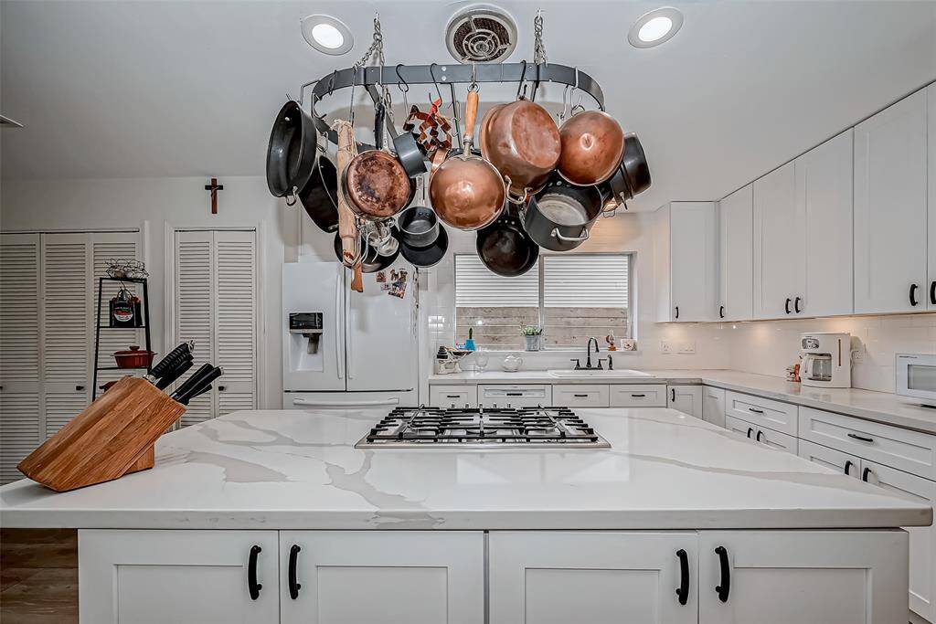 Kitchen island with cooktop and hanging pot rack