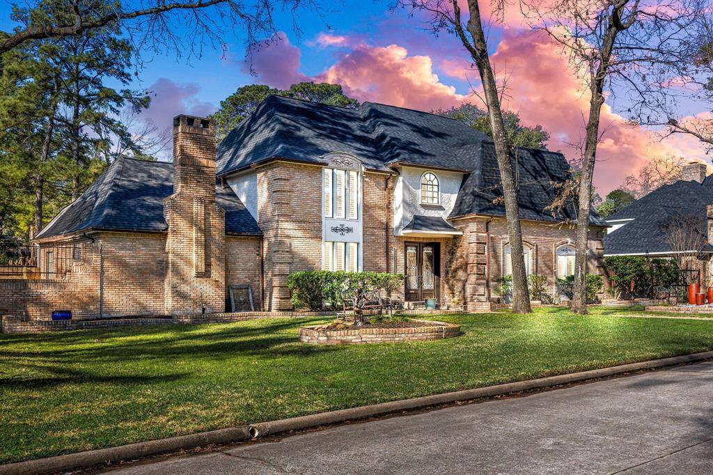 Charming two-story brick home with a classic design, featuring a steep roof and arched windows. Surrounded by mature trees and a pristine lawn, it offers a serene and inviting atmosphere.