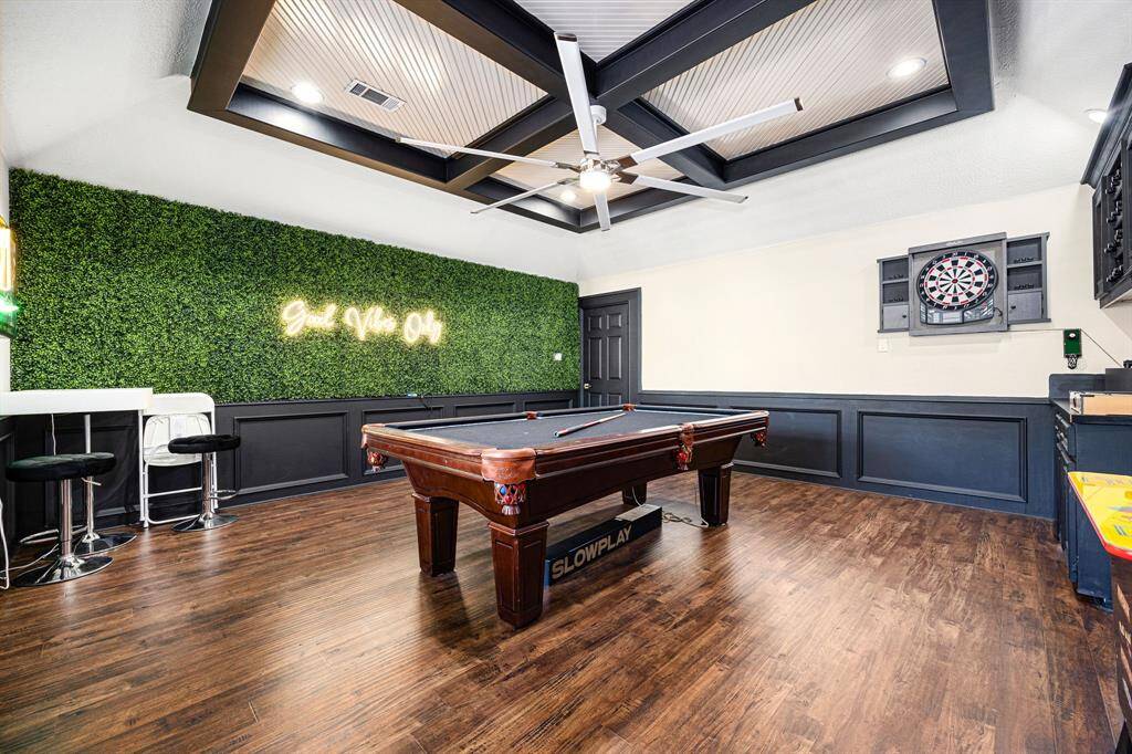 Experience ultimate entertainment in this stylish game room featuring a pool table, dartboard, and chic bar area. Enjoy the modern ceiling with recessed lighting and fan, vibrant greenery wall, and the inviting "Good Vibes Only" neon sign, all set on elegant wood flooring.