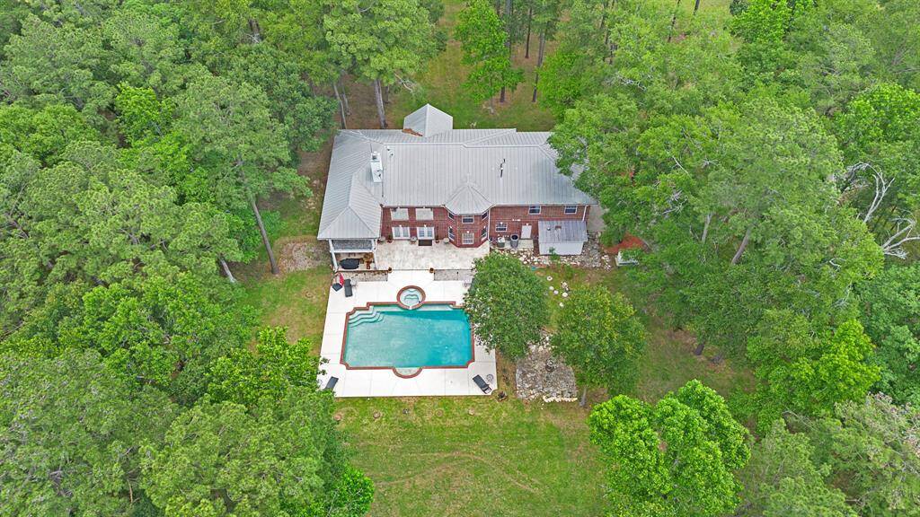 Aerial view of the home with a large pool and surrounding trees