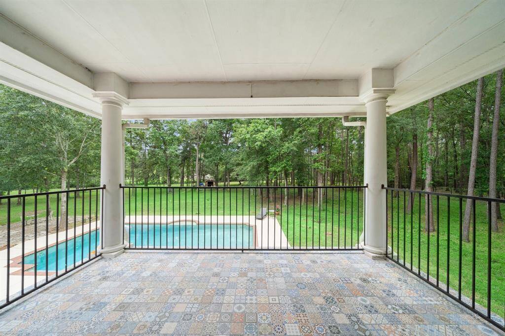 Covered balcony overlooking the pool and lush backyard