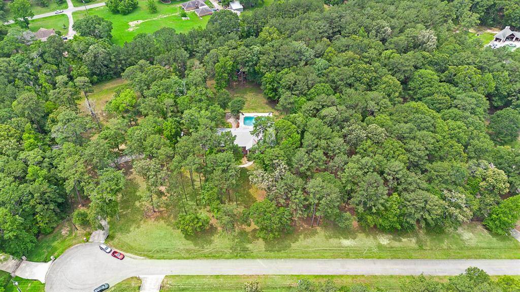Aerial view of the property with a pool and surrounding trees