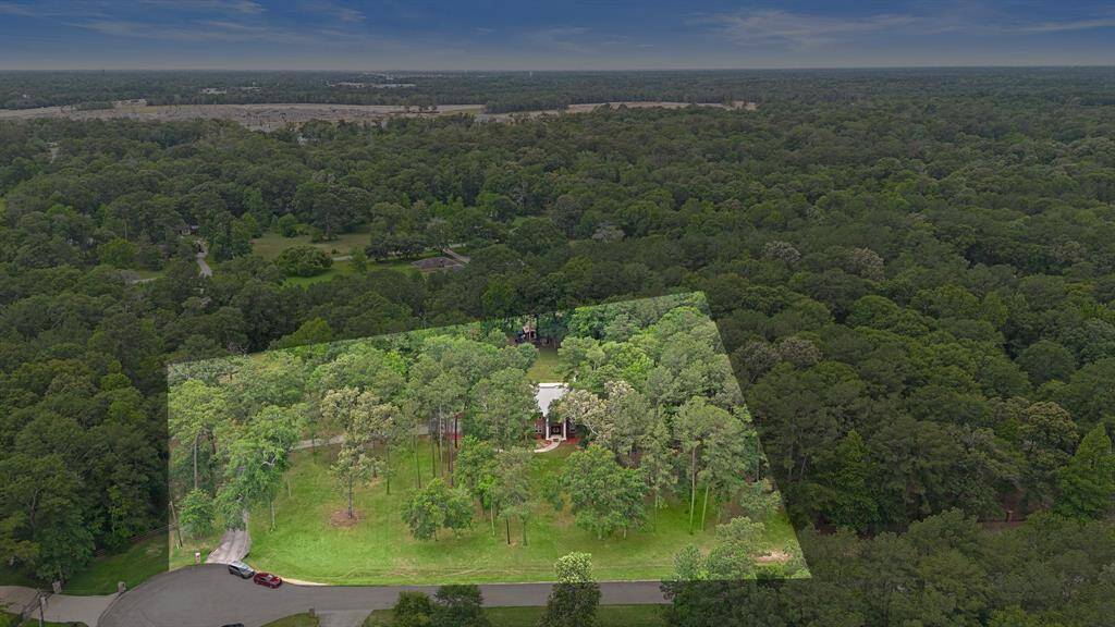 Aerial view highlighting the property within the wooded area.