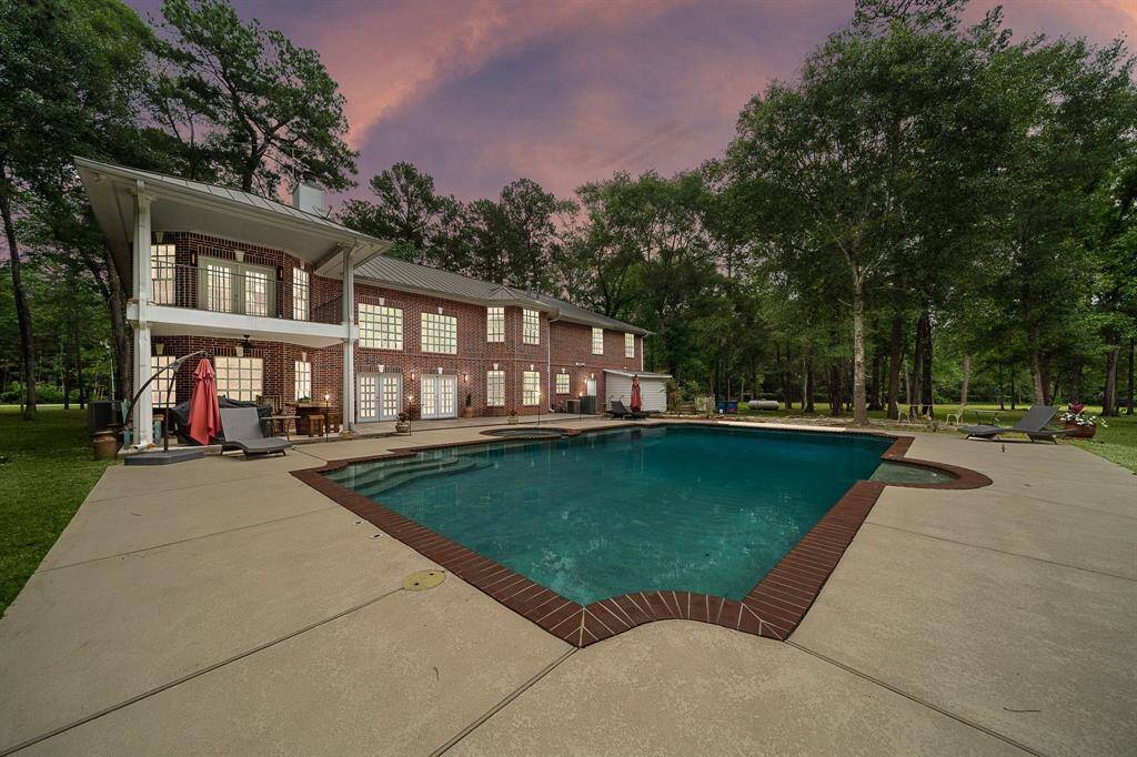 Backyard view of the home with a large pool and patio.