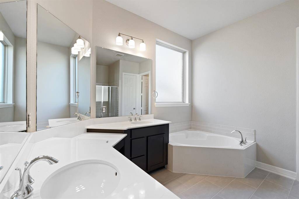 The en-suite bathroom offers a spa-like atmosphere with its elegant design, high end finishes, and tasteful lighting, creating a retreat within your own home.