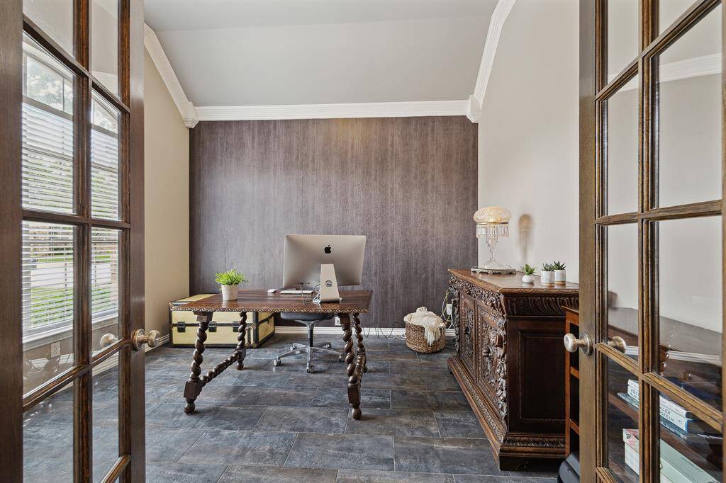 The study. has rich slate tile floors and backdrop of textured wallpaper on the accent wall. Quality millwork on the crown molding.  This is a great size study and would easily accommodate two desks.