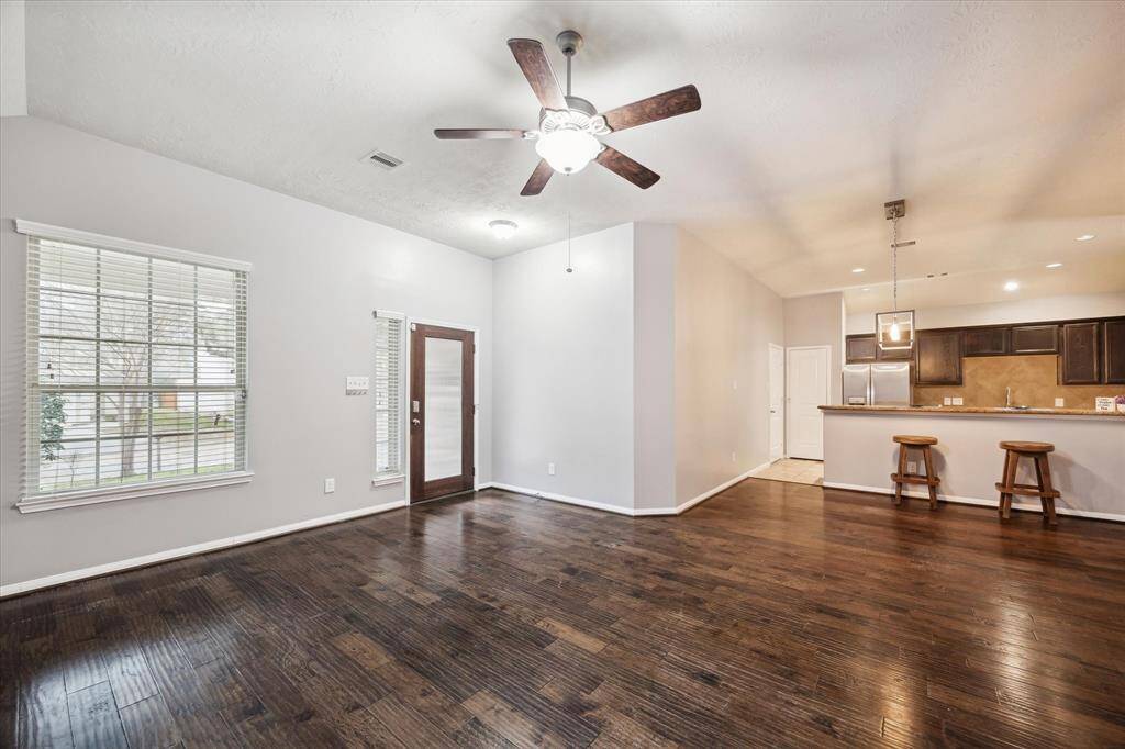 The kitchen features a breakfast bar with pendant lighting, modern stainless steel appliances, and dark wood cabinetry, creating a warm and inviting atmosphere.