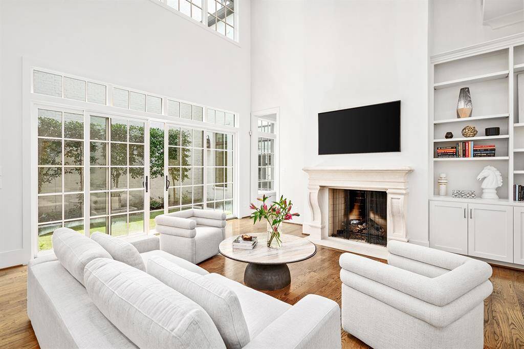 Spacious family room with soaring ceilings, built-ins, cabinet space, fireplace with custom mantel and grand wall of sliding doors providing access back patio/ courtyard.