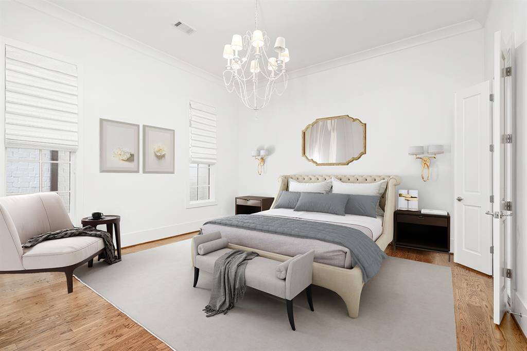 First floor primary bedroom with windows overlooking courtyard and designer chandelier.