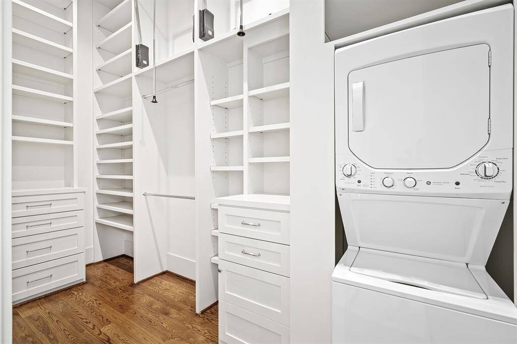 His and hers custom closets with tons of built-ins and shelving and laundry machine located in one closet.