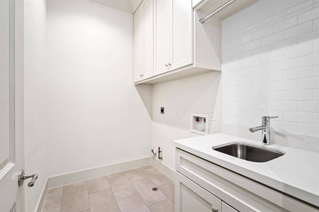 Utility room located on the second floor with sink, and storage space.