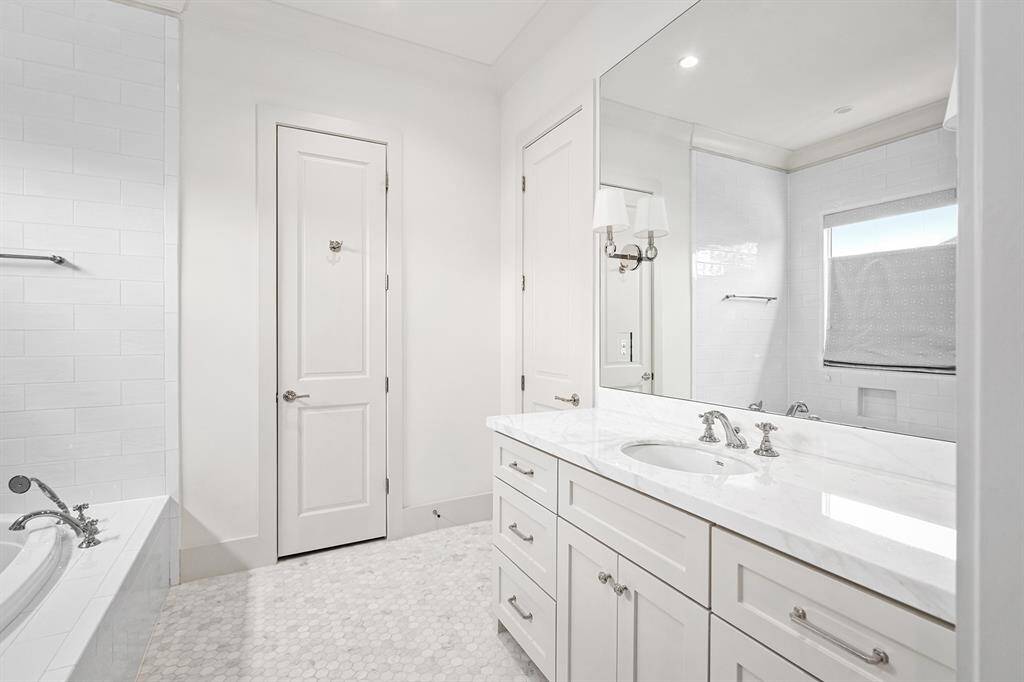 Secondary bathroom with separate soaking tub and walk-in frameless shower, huge vanity space with ample cabinetry, and walk-in closet.