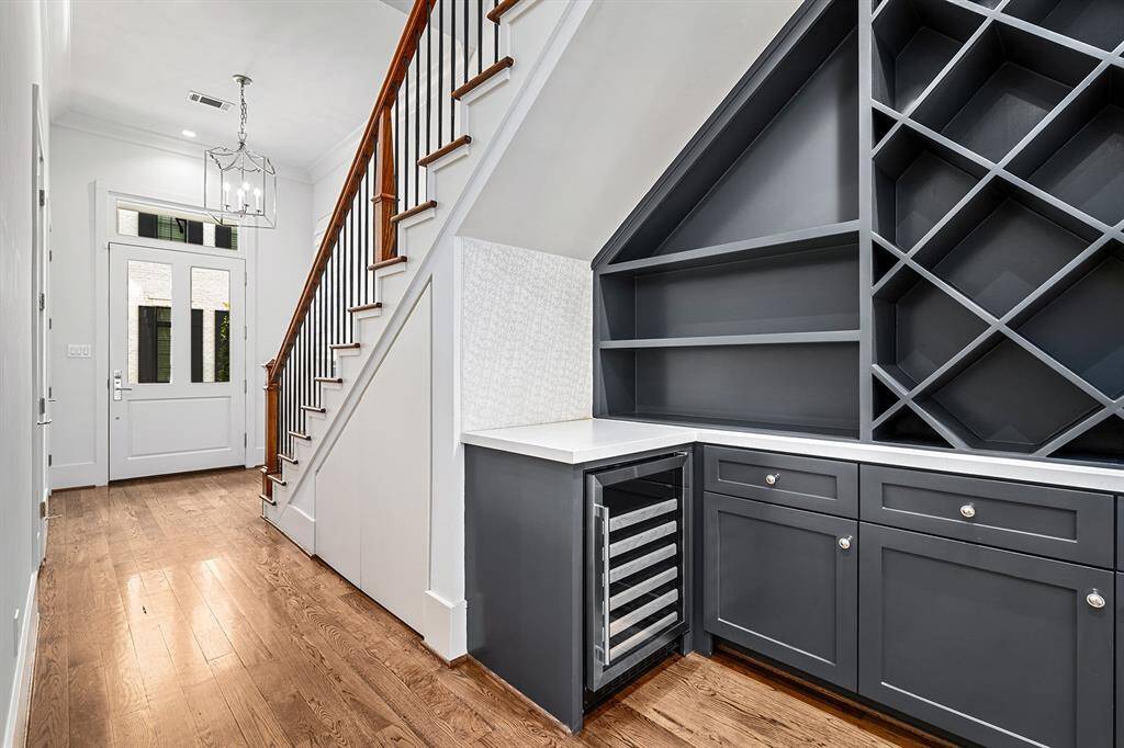 Upon entry, access to stairwell with wood flooring throughout. Wine vault with open shelving, cabinetry, and wine fridge.