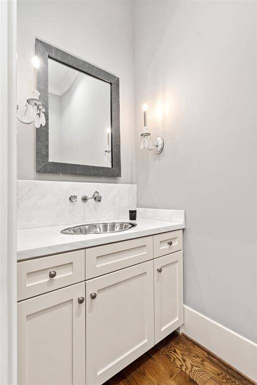 Powder bath located on first floor with marble countertops, designer light fixtures, vintage sink, and cabinet space.