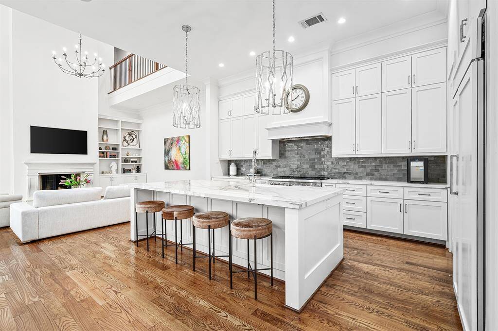 Light and bright kitchen with SS appliances, modern tile backsplash, recessed lighting with additional custom pendant lighting, oversized island with farmhouse style sink and additional seating space, ample storage space throughout, soft closing drawers and cabinets.